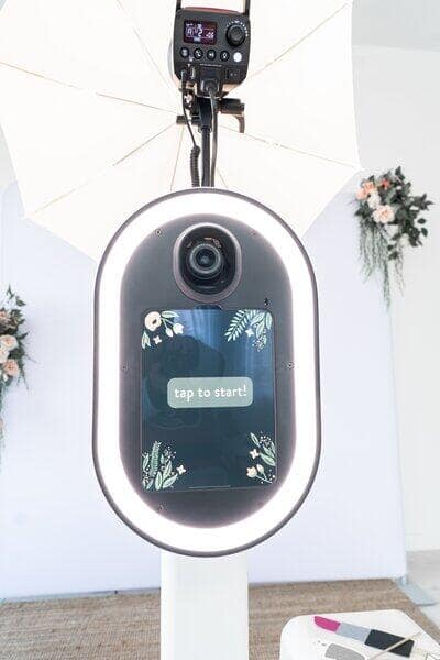 a video of a photobooth with a white light surrounding it, the middle of the booth says tap to start